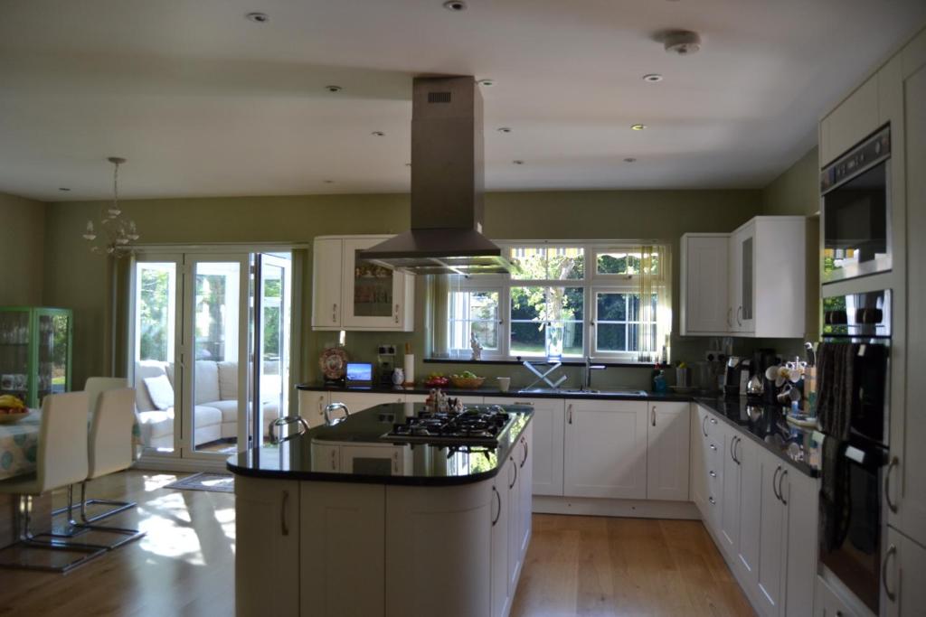 a kitchen with white cabinets and a stove top oven at Leafy Suburban Bed and Breakfast in Northwood