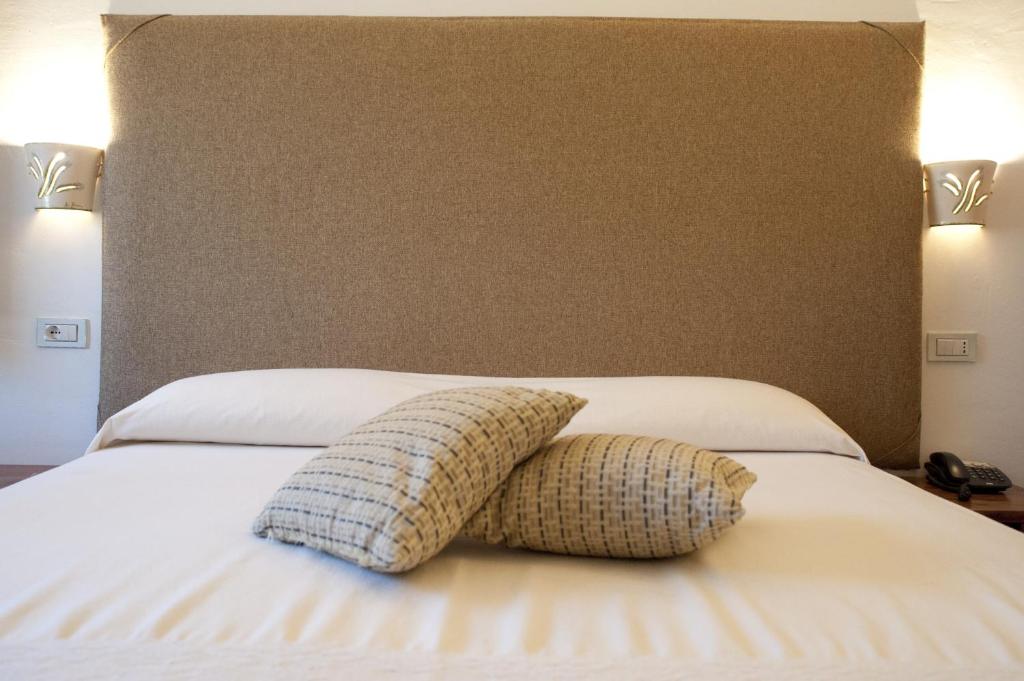 a bed with two pillows on top of it at Nascar Hotel in Santa Maria Navarrese