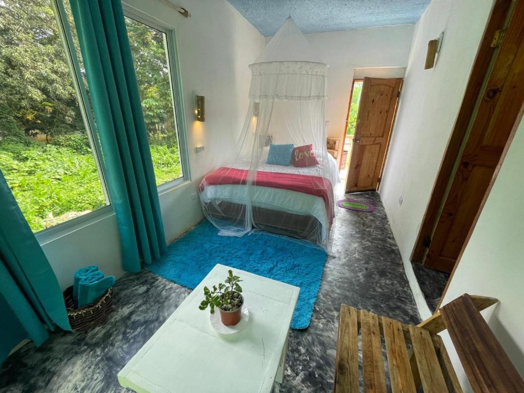 a bedroom with a bed and a table and window at Salvaje Rooms&Restaurant in Santa Bárbara de Samaná