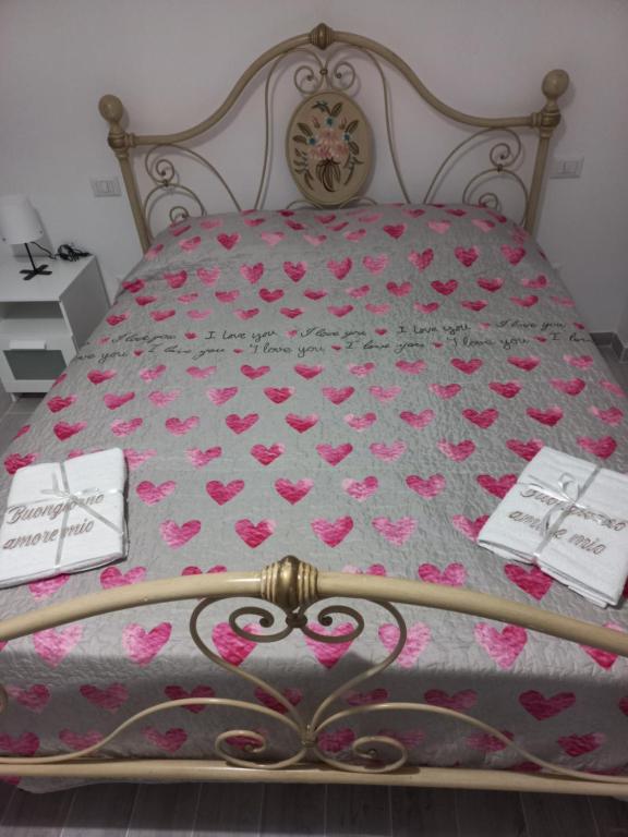 ein Bett mit rosa Herzen darauf mit zwei Karten in der Unterkunft Villa Clotilde in Civitanova Marche