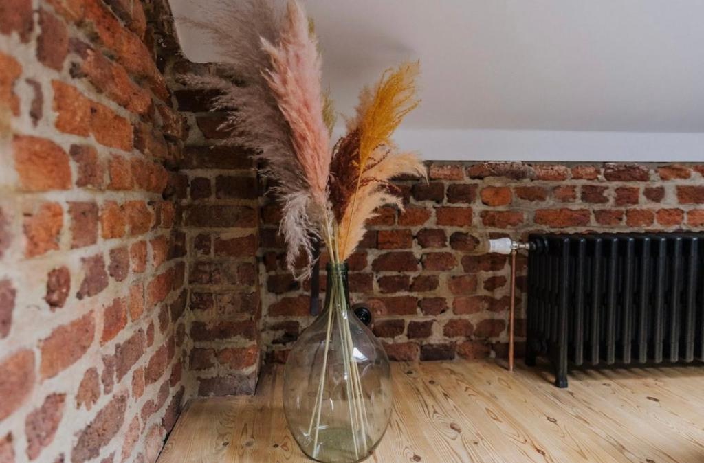 a glass vase with feathers in a brick wall at Au Numéro 5 in Tilff