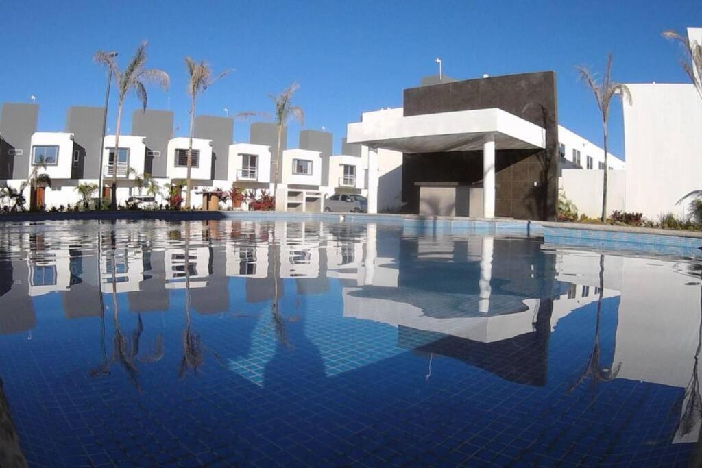una piscina frente a un edificio con palmeras en CIELITO LINDO casa de lujo con alberca 3 habitaciones, en Mezcales