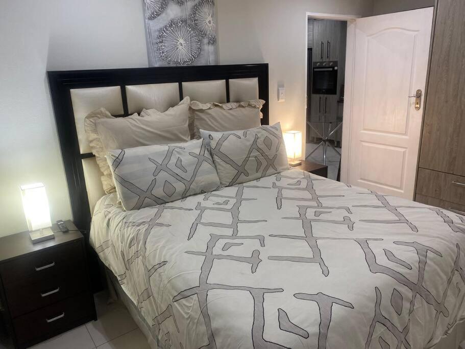 a bedroom with a bed with a black and white comforter at One Bedroom Luxury Apartment in Pretoria