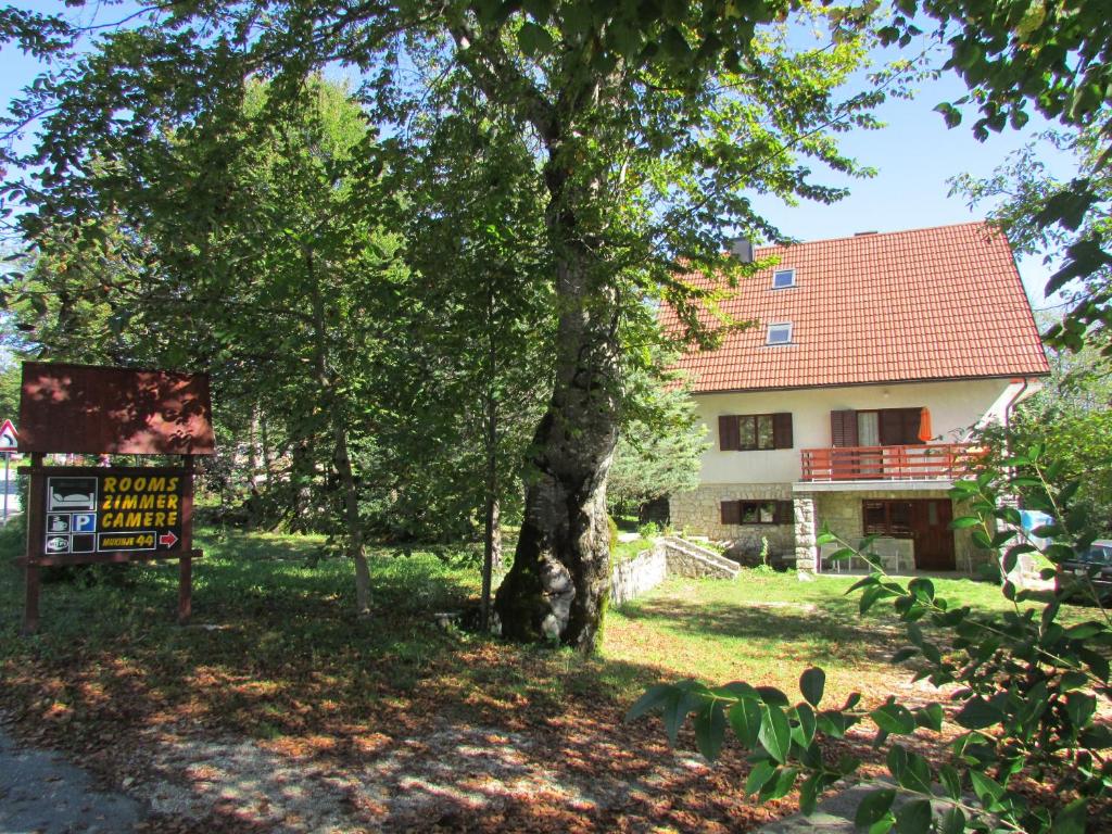 
a tree in front of a house with a sign at Guest House Nenad in Plitvička Jezera
