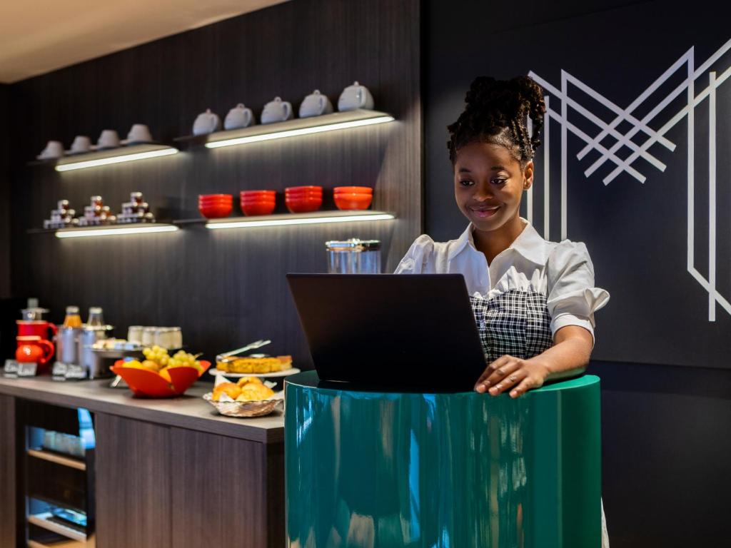 a young girl standing behind a counter with a laptop at MOKA Hôtel in Lorient