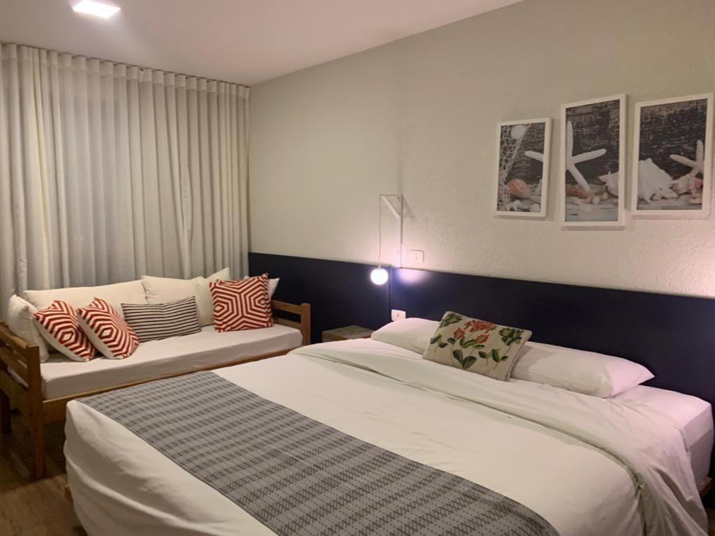 een hotelkamer met 2 bedden en een bank bij Apartamento em Resort Angra dos Reis in João Neiva