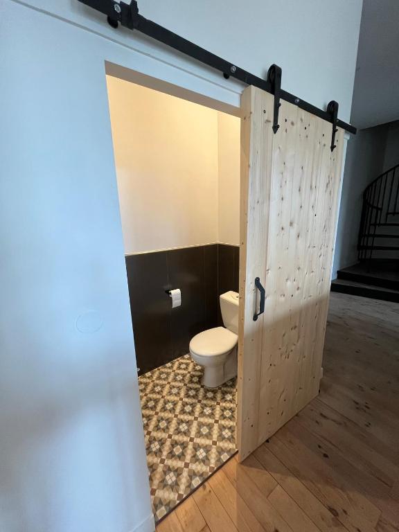 a bathroom with a toilet and a wooden door at Gite du Prieuré in Chagny