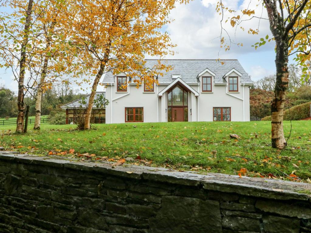 une maison blanche avec un mur en pierre et des arbres dans l'établissement Hazelwood, à Leap