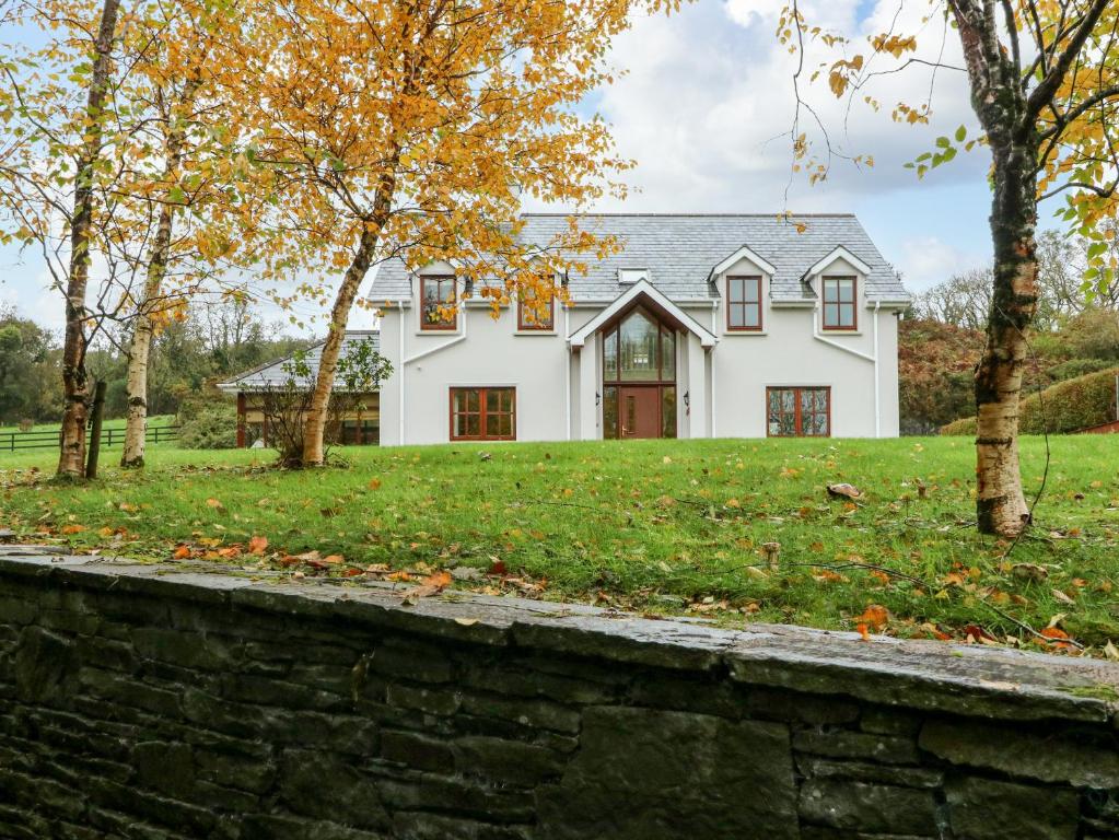 a white house with a stone wall and trees at Hazelwood in Leap