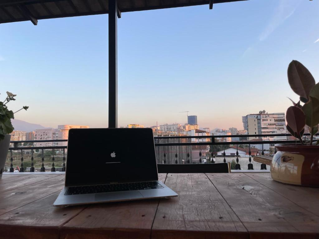 a laptop sitting on a wooden table on a balcony at Cozy big apartment with balcony in Tirana