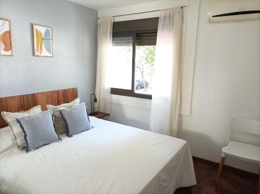 a bedroom with a white bed with blue pillows at Buenaventura Apartments Terrazas in Mendoza