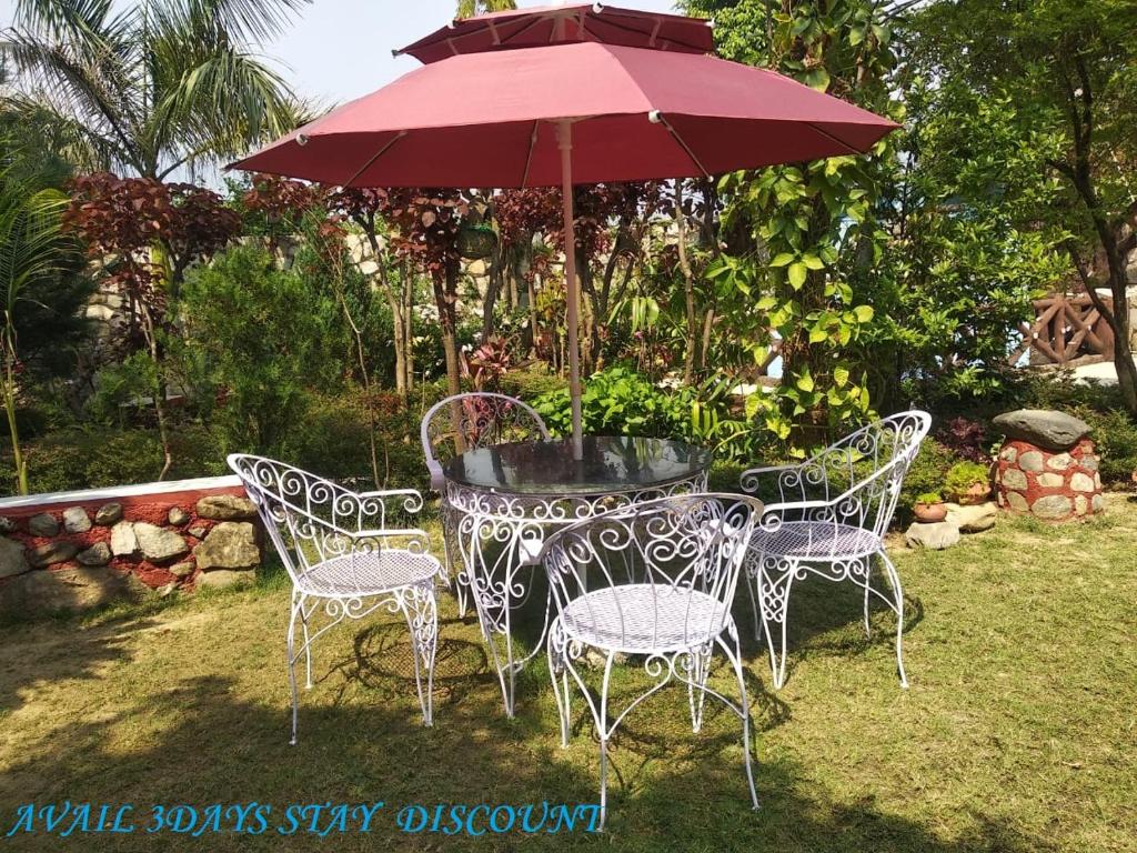 un tavolo e sedie sotto un ombrellone rosso di Oxygen Homestay a Dehradun