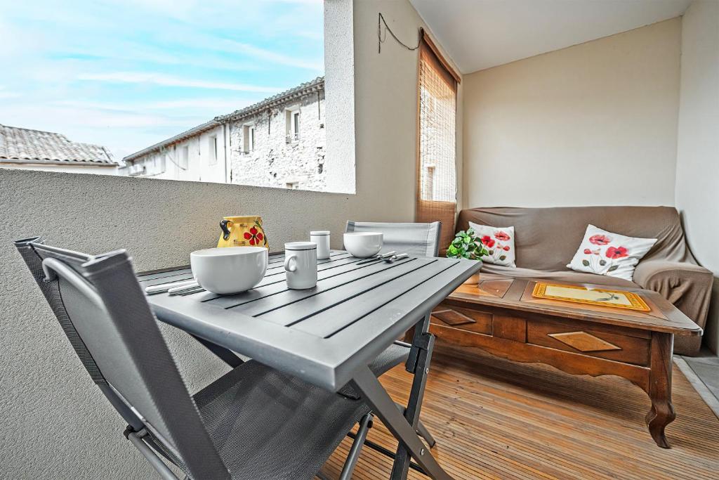 un tavolo e sedie in legno su un balcone con tavolo di Îlot COQUELICOT - PARKING GRATUIT SECURISE - AC CLiM - ASCENSEUR - BALCON a LʼIsle-sur-la-Sorgue