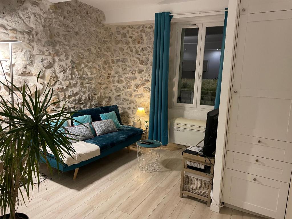 een woonkamer met een blauwe bank en een tv bij Appartement La Tourraque côté mer in Antibes