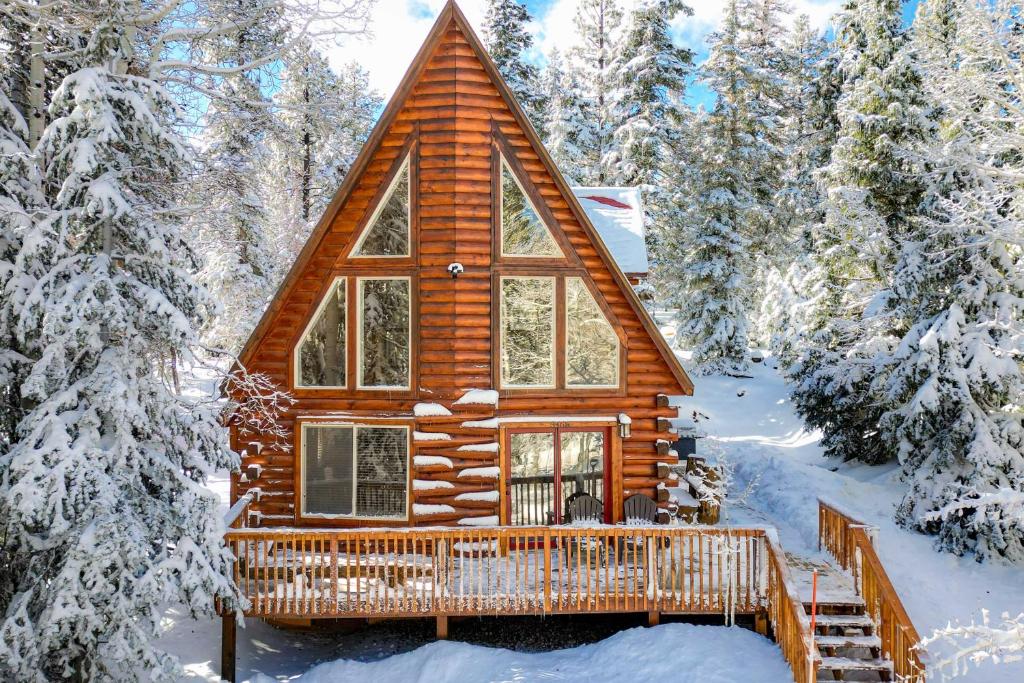 a log cabin in the woods in the snow at Walk to Duck Creek Village A-Frame Getaway! in Duck Creek Village
