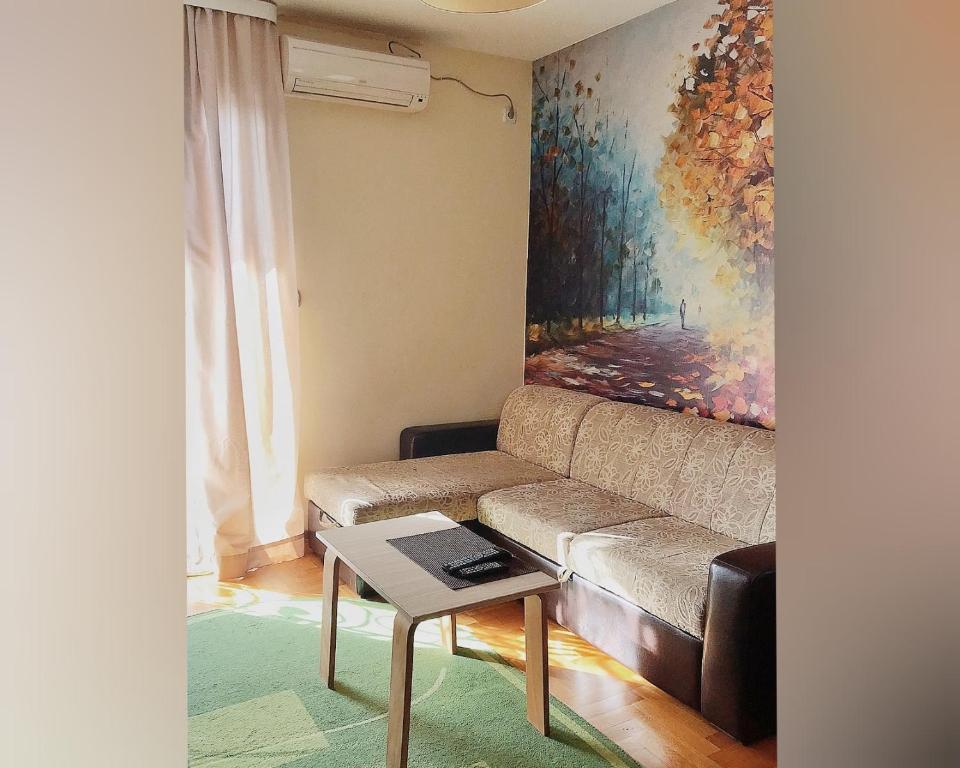 ein Wohnzimmer mit einem Sofa und einem Gemälde in der Unterkunft Apartmani IVANA in Vrnjačka Banja