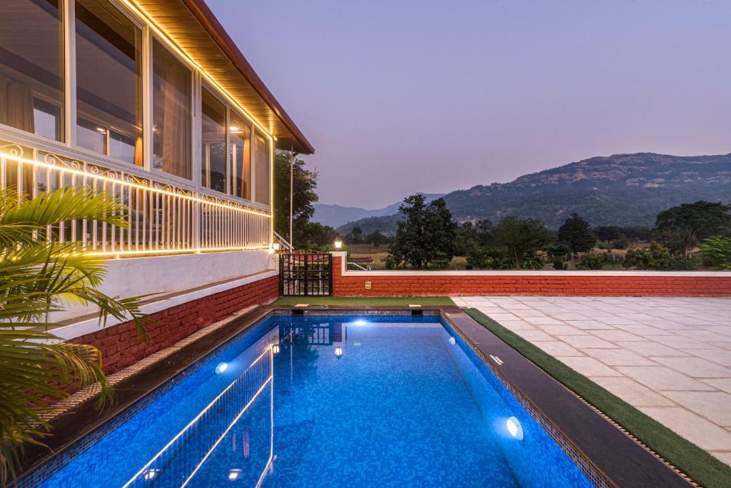 einen Pool im Hinterhof eines Hauses in der Unterkunft SaffronStays Olive Greens, Karjat in Karjat