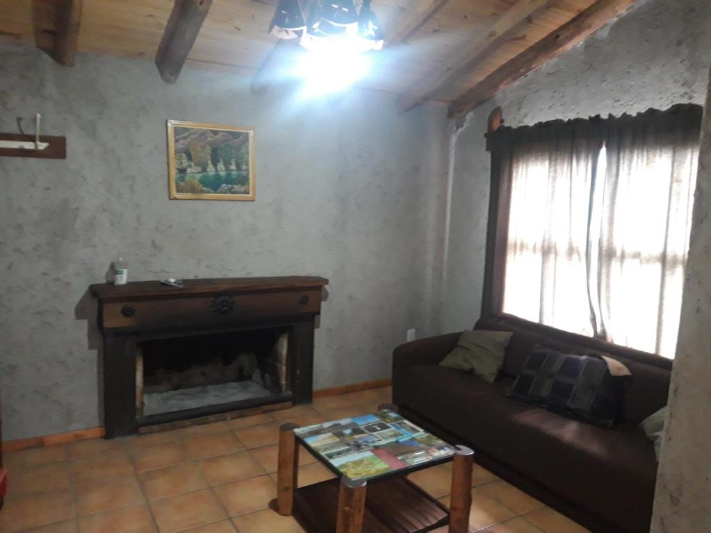 sala de estar con sofá y chimenea en Cabaña Manzano Histórico en Tunuyán
