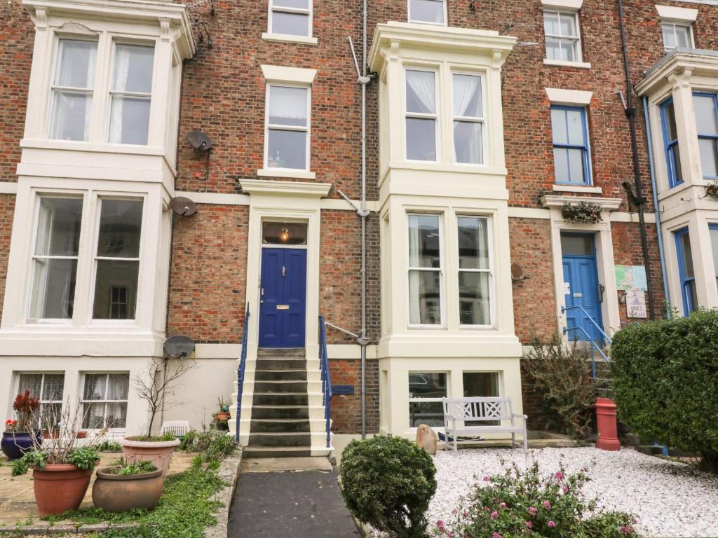 a brick house with a blue door and stairs at Abbey Vista in Whitby