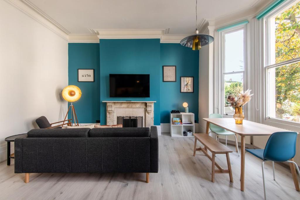 ein Wohnzimmer mit einem schwarzen Sofa und einer blauen Wand in der Unterkunft Newly Renovated Central Modern Apartment in Brighton & Hove