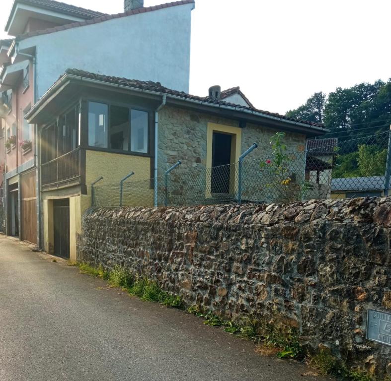 uma casa de pedra com uma parede de pedra ao lado de uma rua em La casina del Güeña em Cangas de Onís