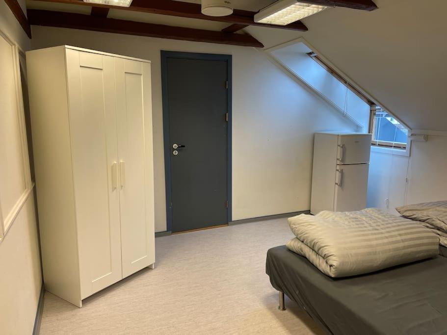a room with a bed and a door and a refrigerator at Lillehammer Guest House with common bath and kitchen in Lillehammer