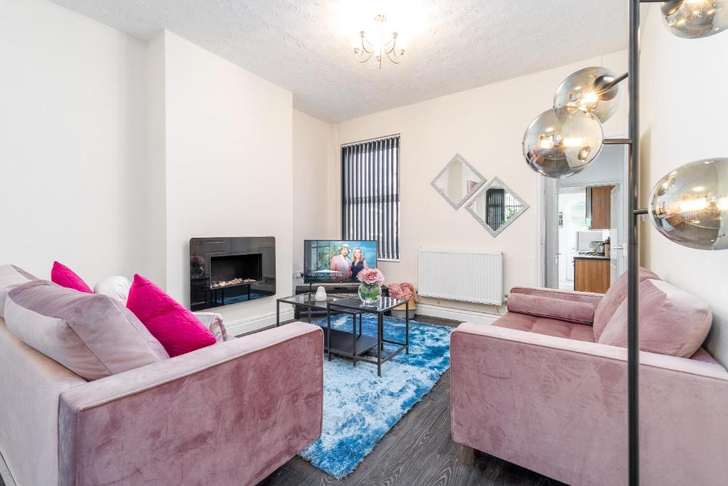 a living room with two pink couches and a tv at Spacious 2 bed house with free on street parking in Birmingham