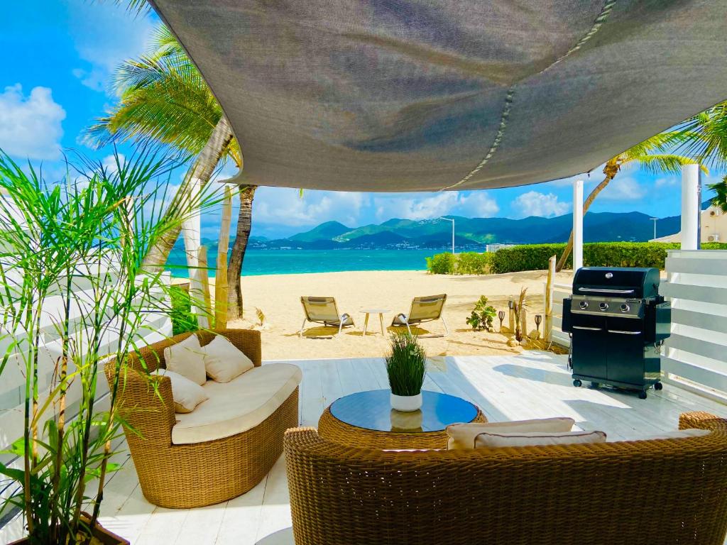 a patio with chairs and a grill on the beach at Villa cocoon sur la plage in Saint Martin