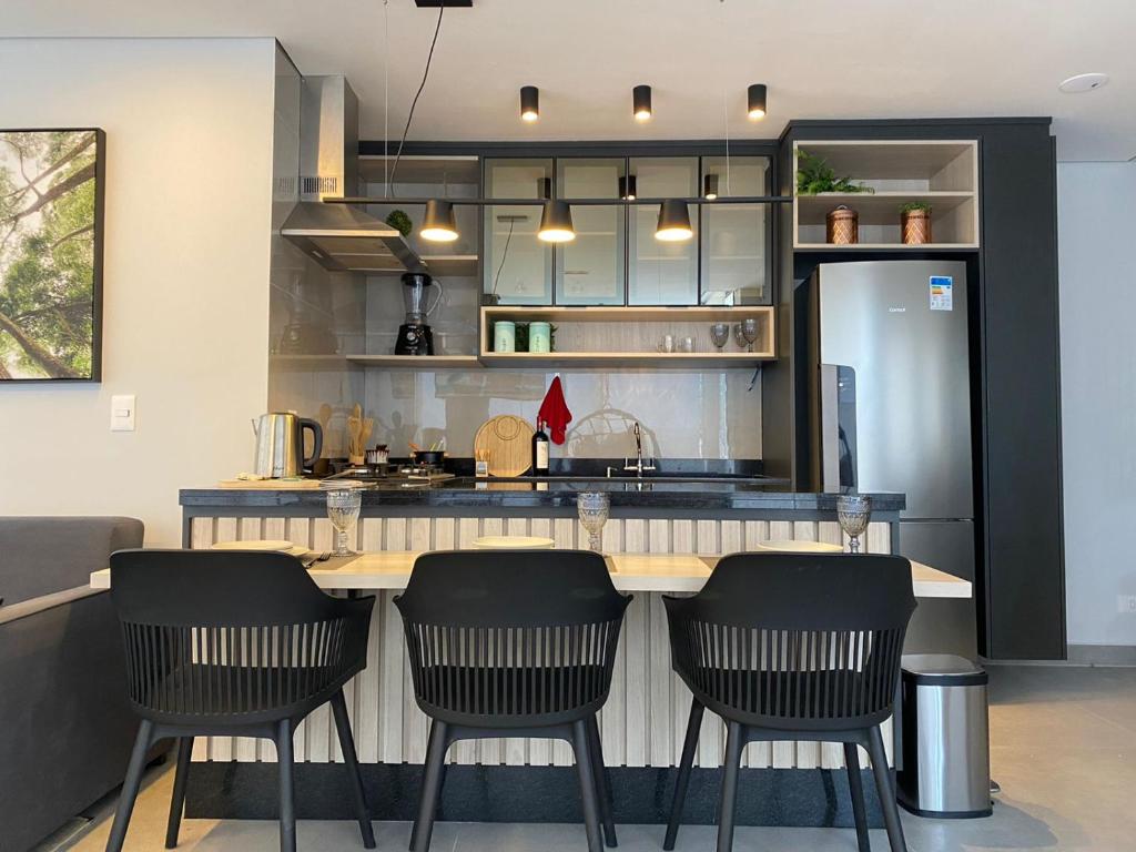 una cocina con una barra con 4 sillas alrededor en Lindo Apartamento com banheira e linda vista a 500 m do Capivari, en Campos do Jordão