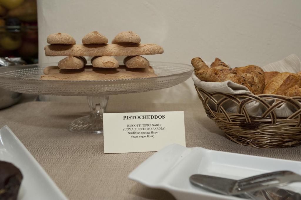 a plate of cookies on a table with a basket of bread at Nascar Hotel in Santa Maria Navarrese