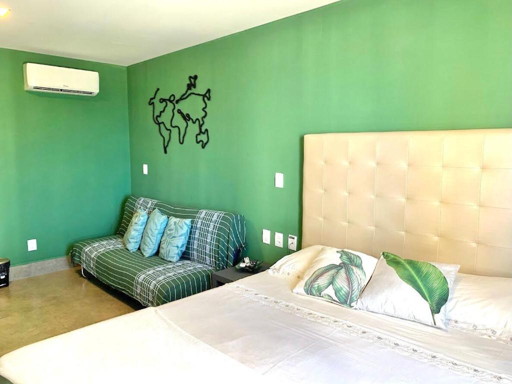 een groene slaapkamer met een bed en een bank bij Ilusion: perto de tudo em Ponta Negra - AlfaTemporada in Natal