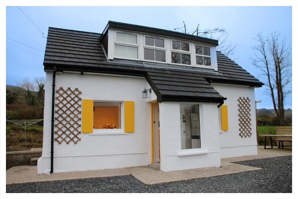 een klein wit huis met gele luiken bij Killeavy Cottage in Meigh