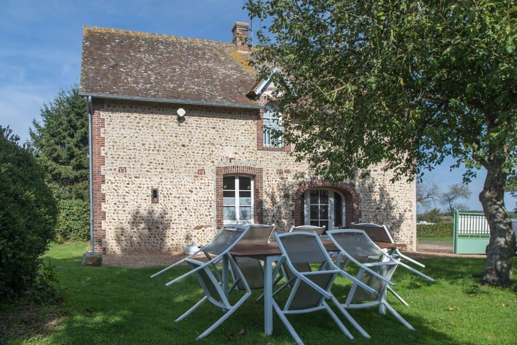 a table and chairs in front of a brick house at Les Granges du Bois Normand in Rueil-la-Gadelière