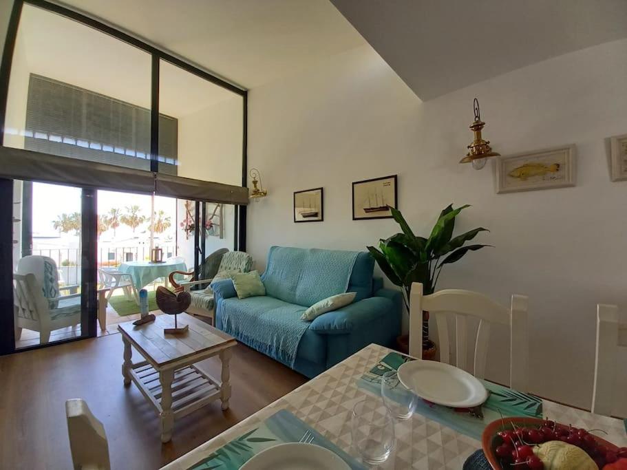 uma sala de estar com um sofá azul e uma mesa em Precioso apartamento en complejo con piscina em Cala'n Bosch