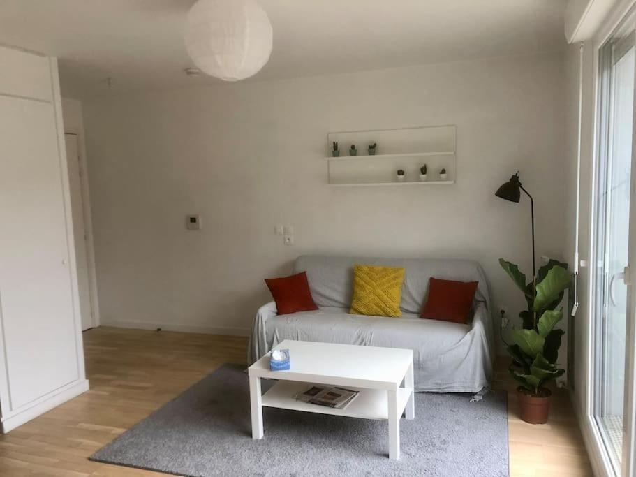 a living room with a white couch and a table at Charmant appartement à la limite de Paris in Villejuif