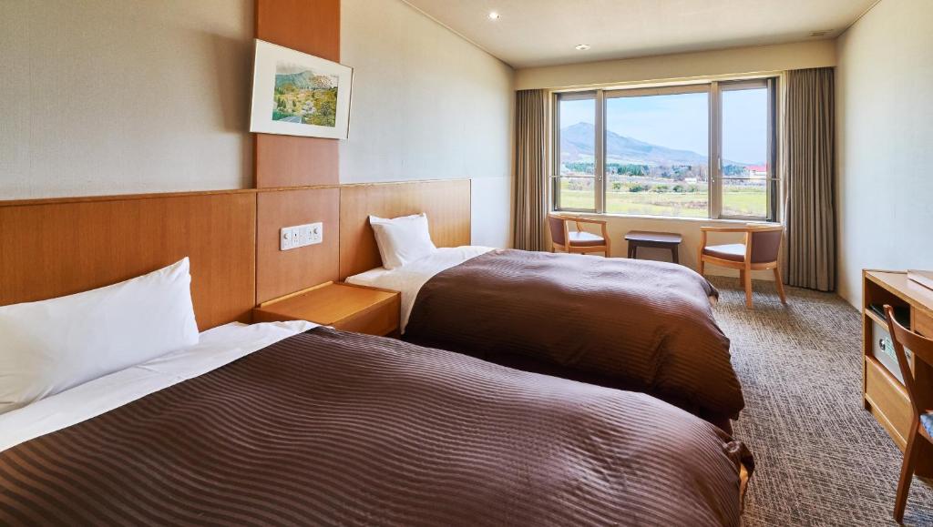 um quarto de hotel com duas camas e uma janela em Kyukamura Hiruzen-Kogen em Maniwa
