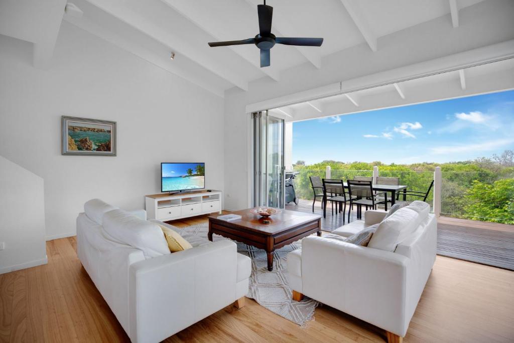 a living room with white furniture and a large window at 2 Casuarinas Peregian Beach in Coolum Beach