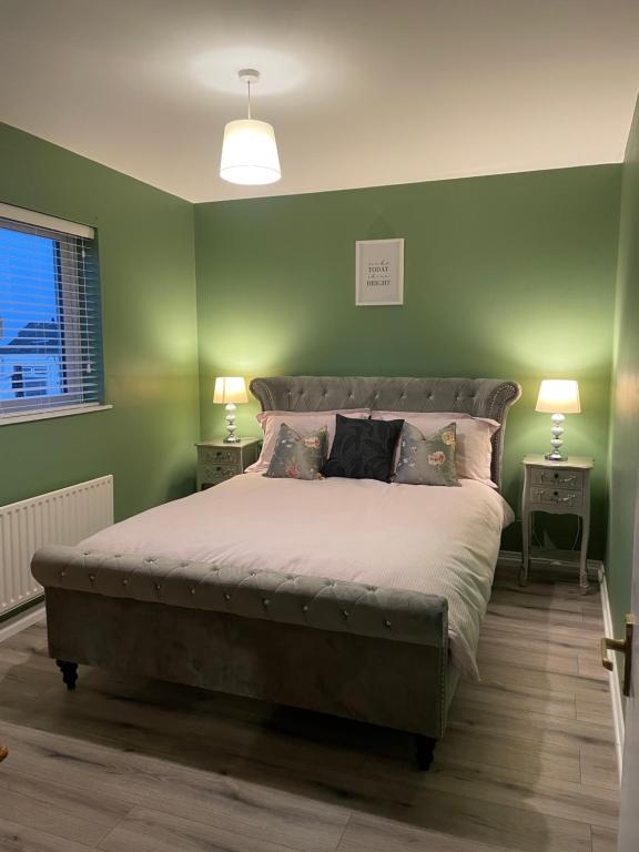 a bedroom with a large bed with green walls at Heights View Apartment in Derry Londonderry