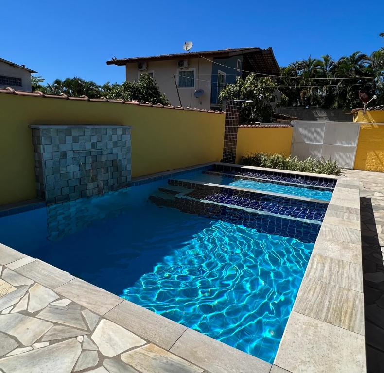 una piscina de agua azul frente a una casa en Casa Temporada en Ubatuba