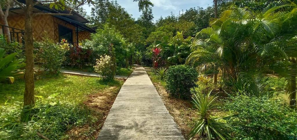 a path through a garden with trees and a house at Koh Mook Bamboo Bungalows in Ko Mook