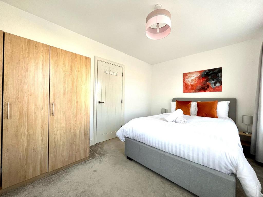 1 dormitorio con 1 cama grande y armario de madera en Lovely 4 doubled bedroomed townhouse in Bicester near to Bicester Village en Bicester