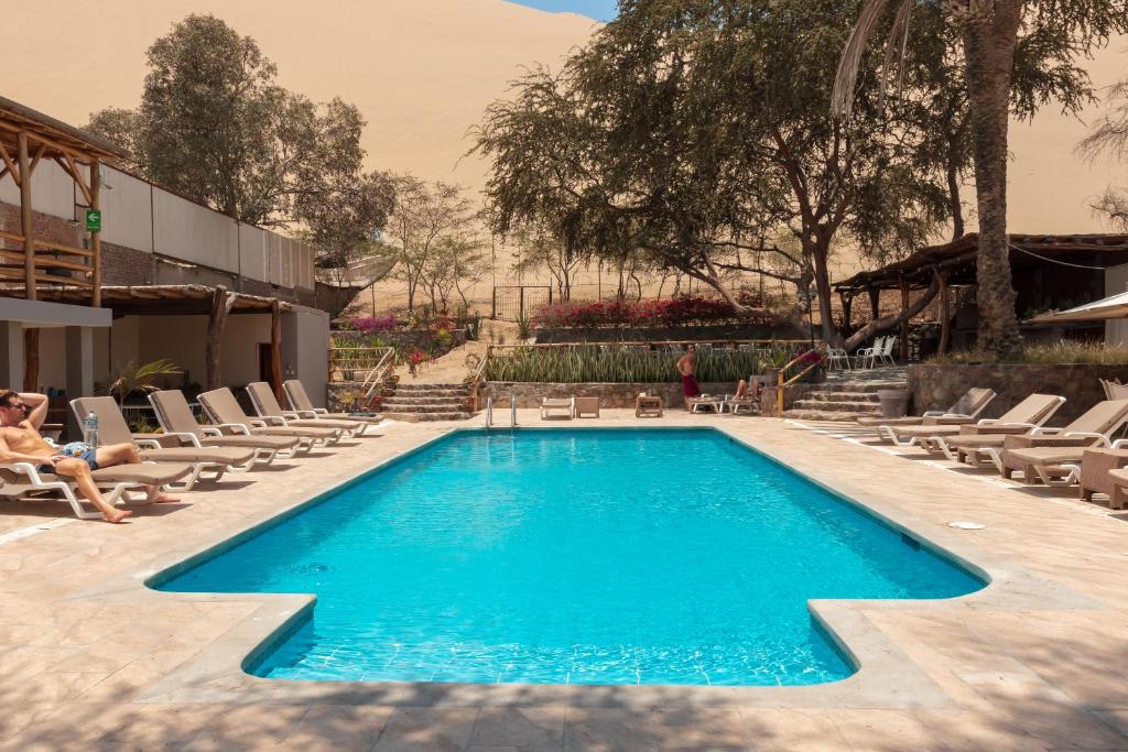 a pool with chaise lounge chairs next to a resort at Hotel El Huacachinero- Hotel Familiar in Ica