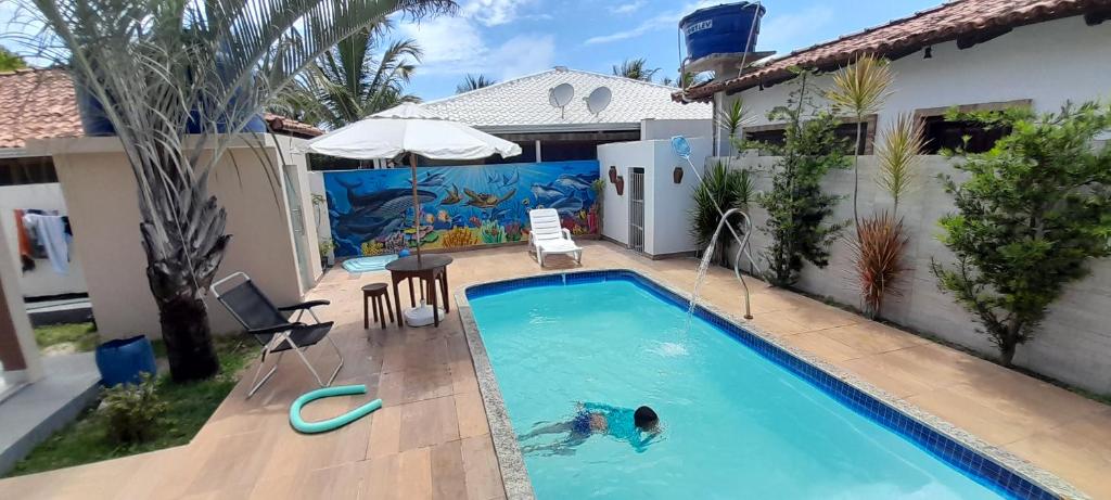 een persoon die zwemt in een zwembad in een huis bij Casa com Piscina em Guaratiba in Prado