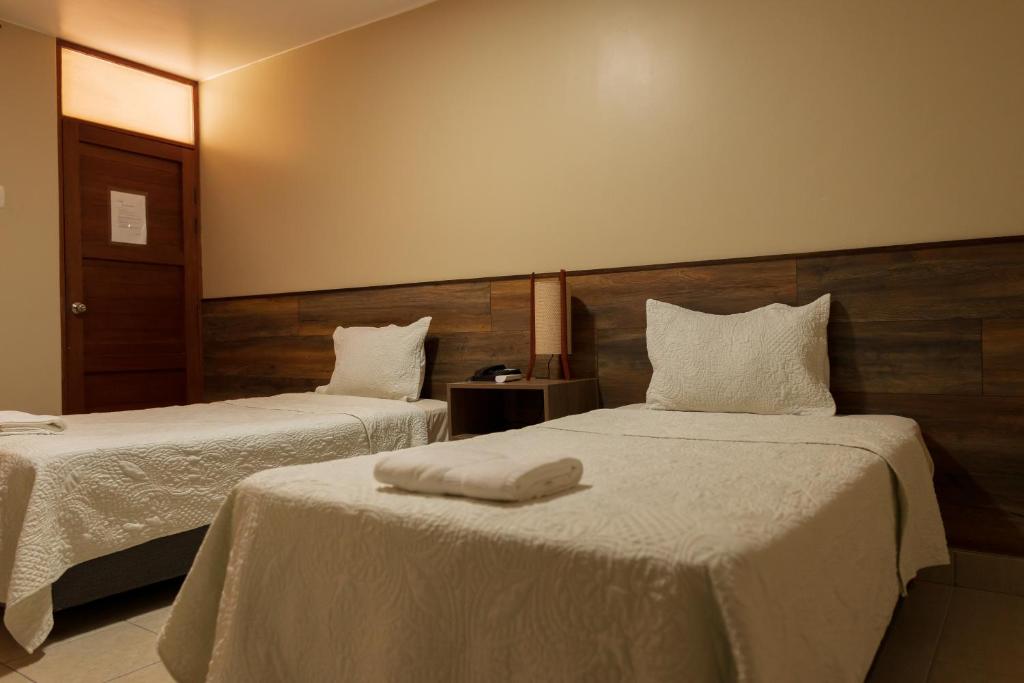 a hotel room with two beds with white sheets at Hotel El Huacachinero in Ica