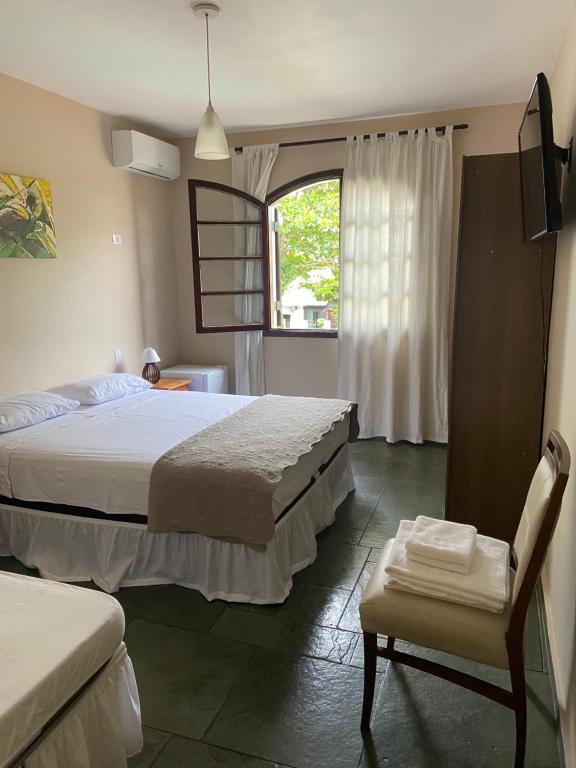 een slaapkamer met 2 bedden, een stoel en een raam bij Pousada As Ondas in Guarujá