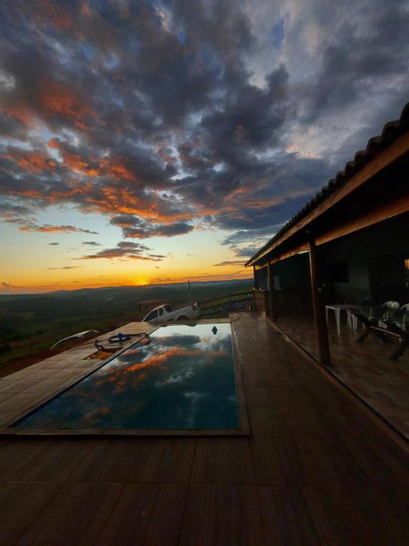 a pool on the deck of a house with a sunset at Chácara do Mirante in São Sebastião do Paraíso
