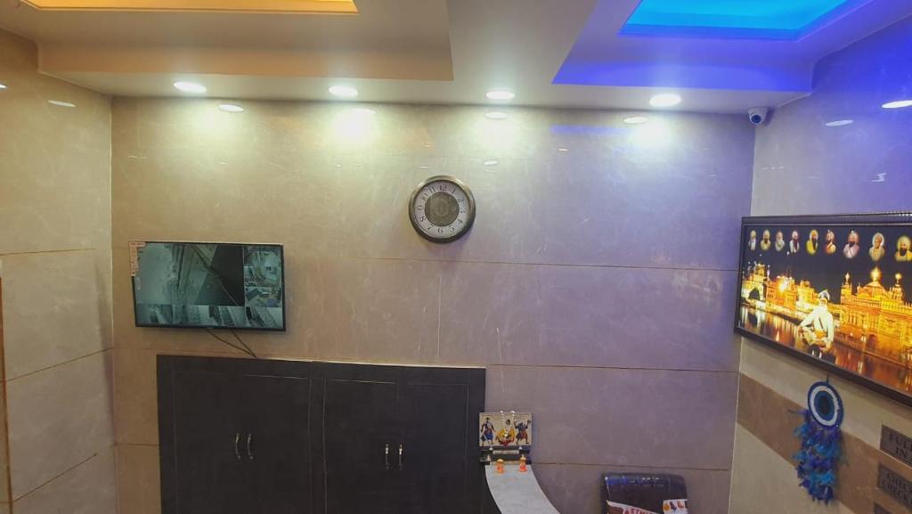 un mur avec une horloge et une télévision sur un mur dans l'établissement Green leaf BnB, à Amritsar