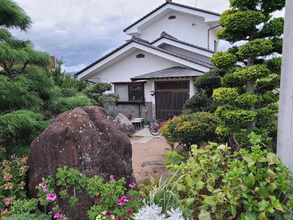 ein Haus mit einem Felsen davor in der Unterkunft ゲストハウス陽だまりの宿 in Tomi