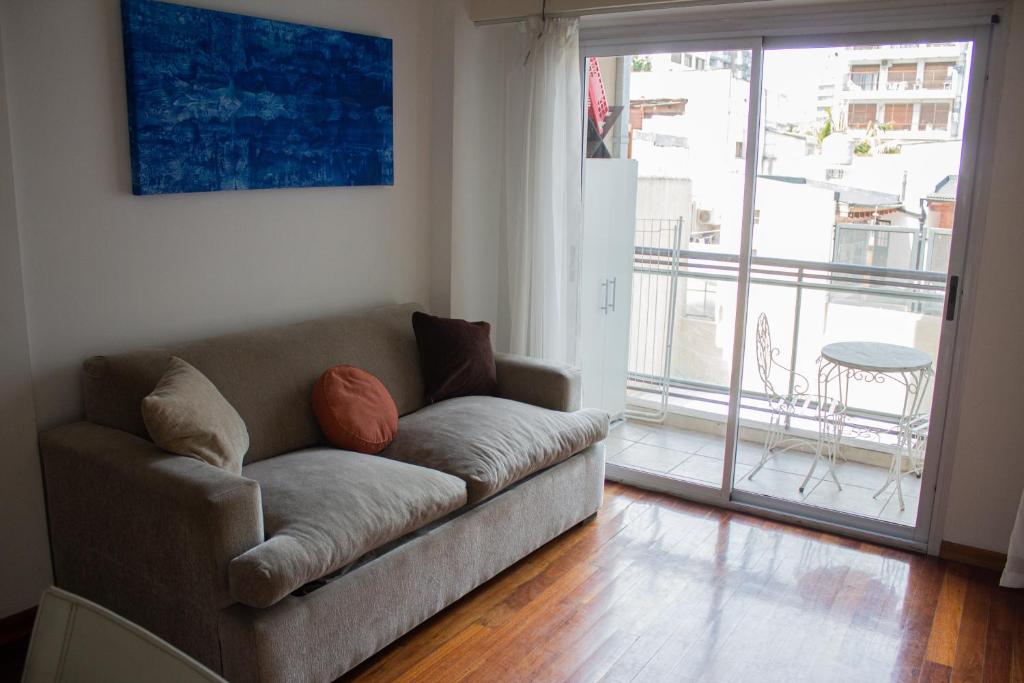 sala de estar con sofá y puerta corredera de cristal en Departamento 3 ambientes con balcón y 2 baños en Buenos Aires