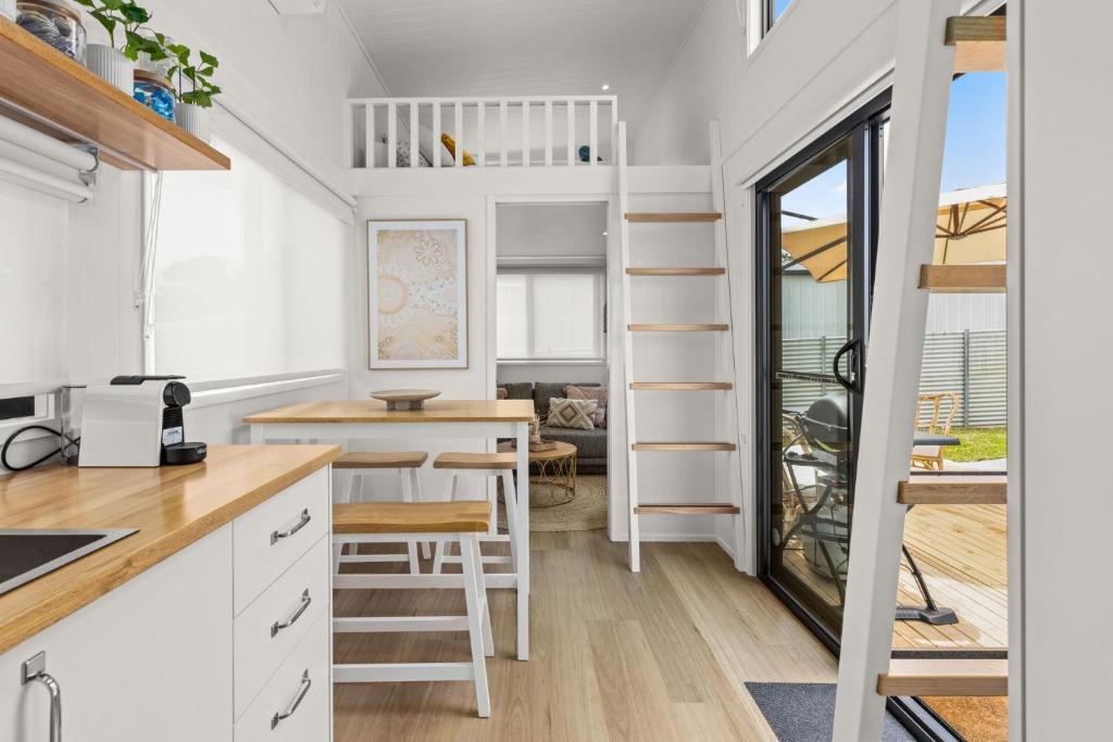 a tiny house with a kitchen and a dining room at Husky Tiny Home by Experience Jervis Bay in Huskisson